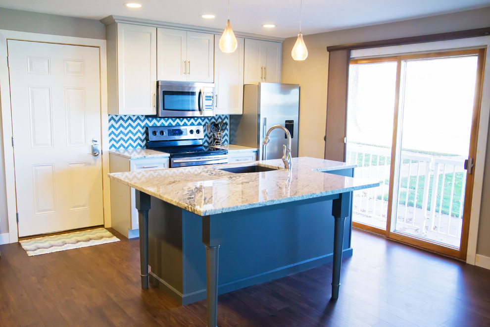 Eat-in kitchen - small transitional galley eat-in kitchen idea with an undermount sink, recessed-panel cabinets, white cabinets, granite countertops, multicolored backsplash, glass tile backsplash, stainless steel appliances and an island
