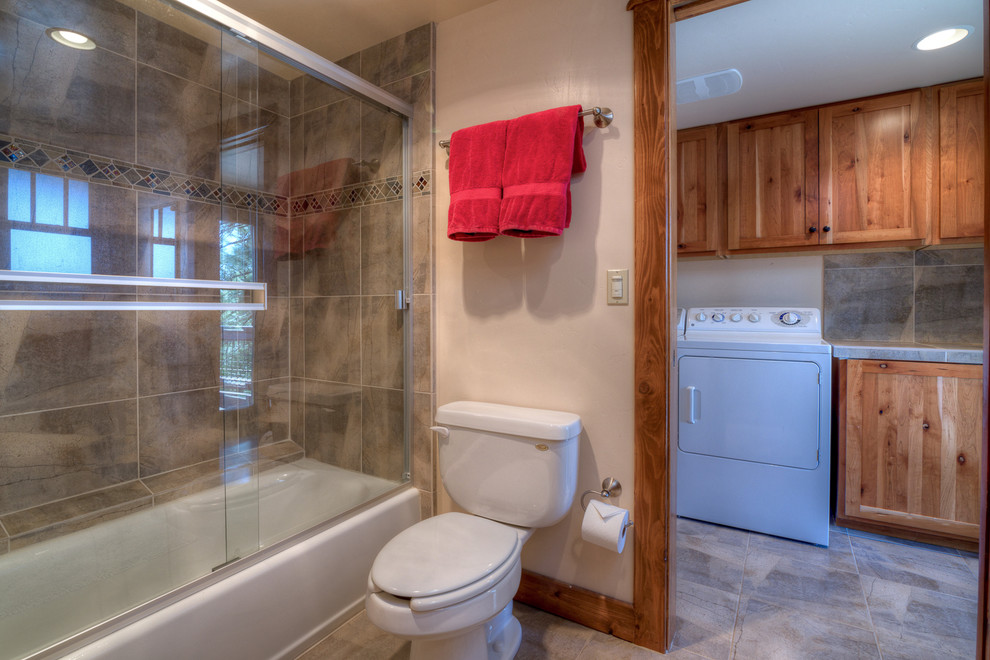 Small arts and crafts 3/4 bathroom in Sacramento with shaker cabinets, medium wood cabinets, an alcove tub, a shower/bathtub combo, a two-piece toilet, beige tile, ceramic tile, white walls, ceramic floors, a drop-in sink, beige floor and a sliding shower screen.