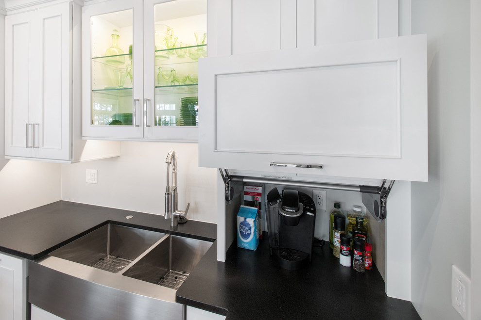 Photo of a large traditional l-shaped eat-in kitchen in Milwaukee with a farmhouse sink, flat-panel cabinets, white cabinets, granite benchtops, stainless steel appliances, medium hardwood floors, with island and yellow floor.