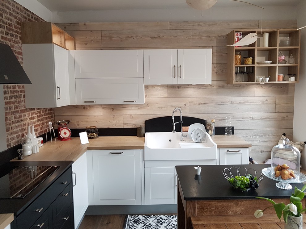 This is an example of a mid-sized modern l-shaped separate kitchen in Dijon with a drop-in sink, beaded inset cabinets, white cabinets, wood benchtops, black splashback, engineered quartz splashback, black appliances, dark hardwood floors, with island, brown floor and brown benchtop.