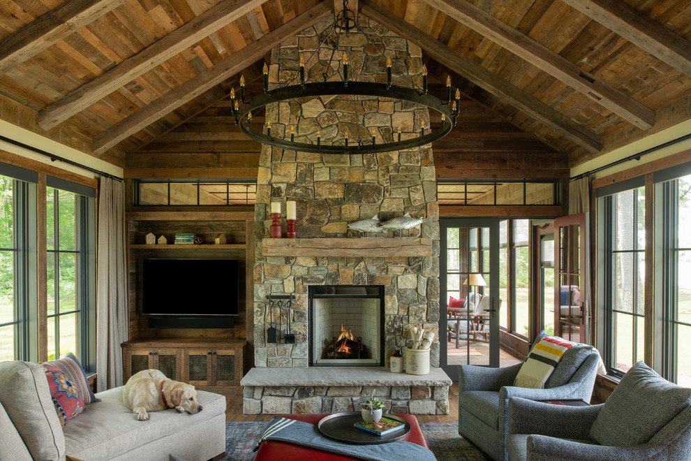Country living room in Minneapolis with white walls, medium hardwood floors, a standard fireplace, a stone fireplace surround, a wall-mounted tv and brown floor.