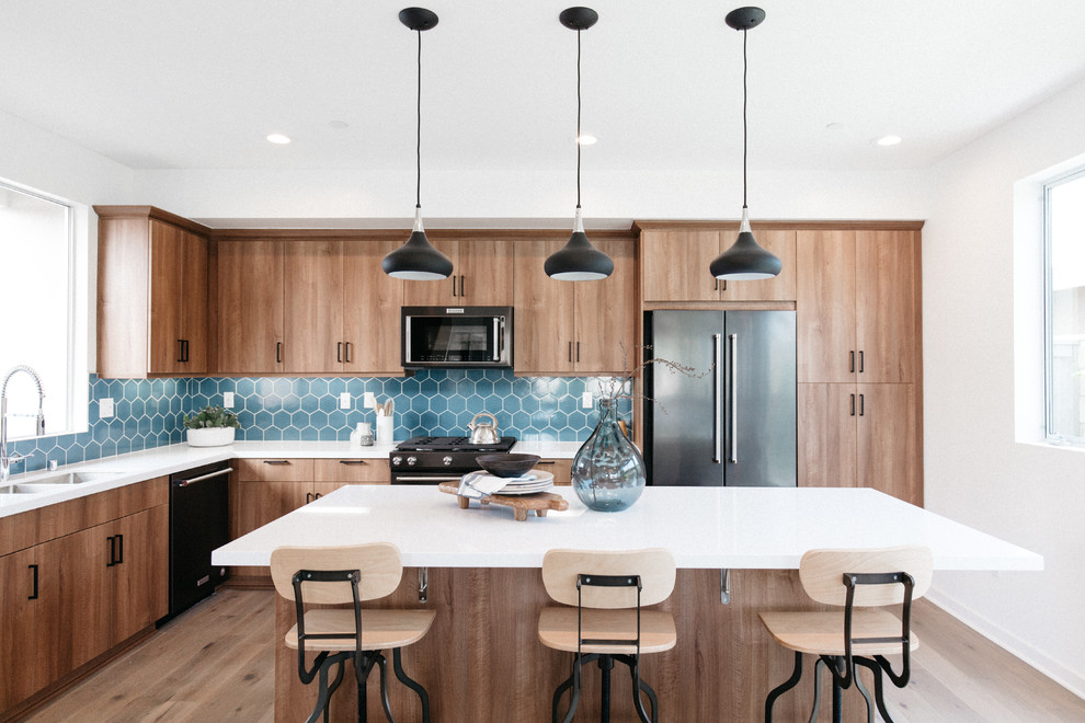 Contemporary l-shaped kitchen in Orange County with an undermount sink, flat-panel cabinets, medium wood cabinets, blue splashback, stainless steel appliances, medium hardwood floors, with island and brown floor.