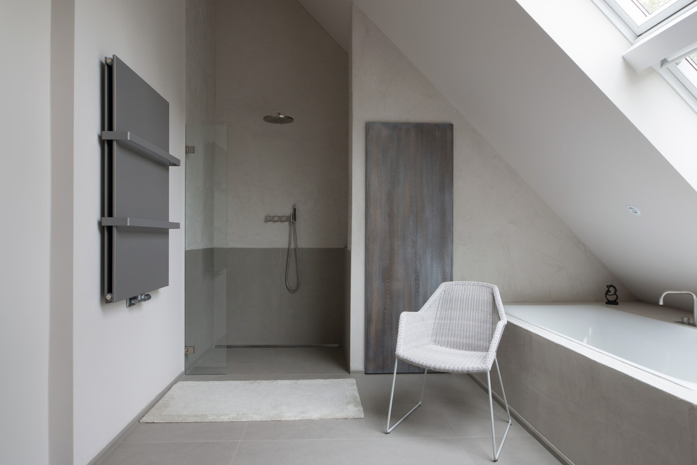 This is an example of a contemporary master bathroom in Berlin with an integrated sink, flat-panel cabinets, dark wood cabinets, marble benchtops, a drop-in tub, a curbless shower, stone slab, grey walls, grey floor and an open shower.