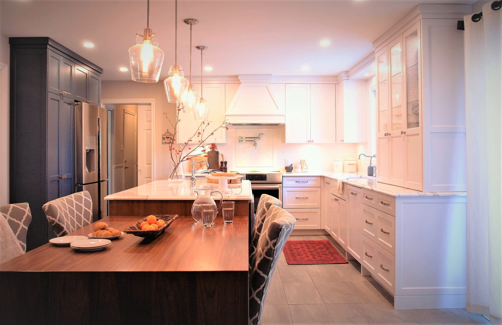 Photo of a large traditional l-shaped eat-in kitchen in Ottawa with a farmhouse sink, shaker cabinets, white cabinets, solid surface benchtops, white splashback, subway tile splashback, stainless steel appliances, porcelain floors, with island, grey floor and multi-coloured benchtop.