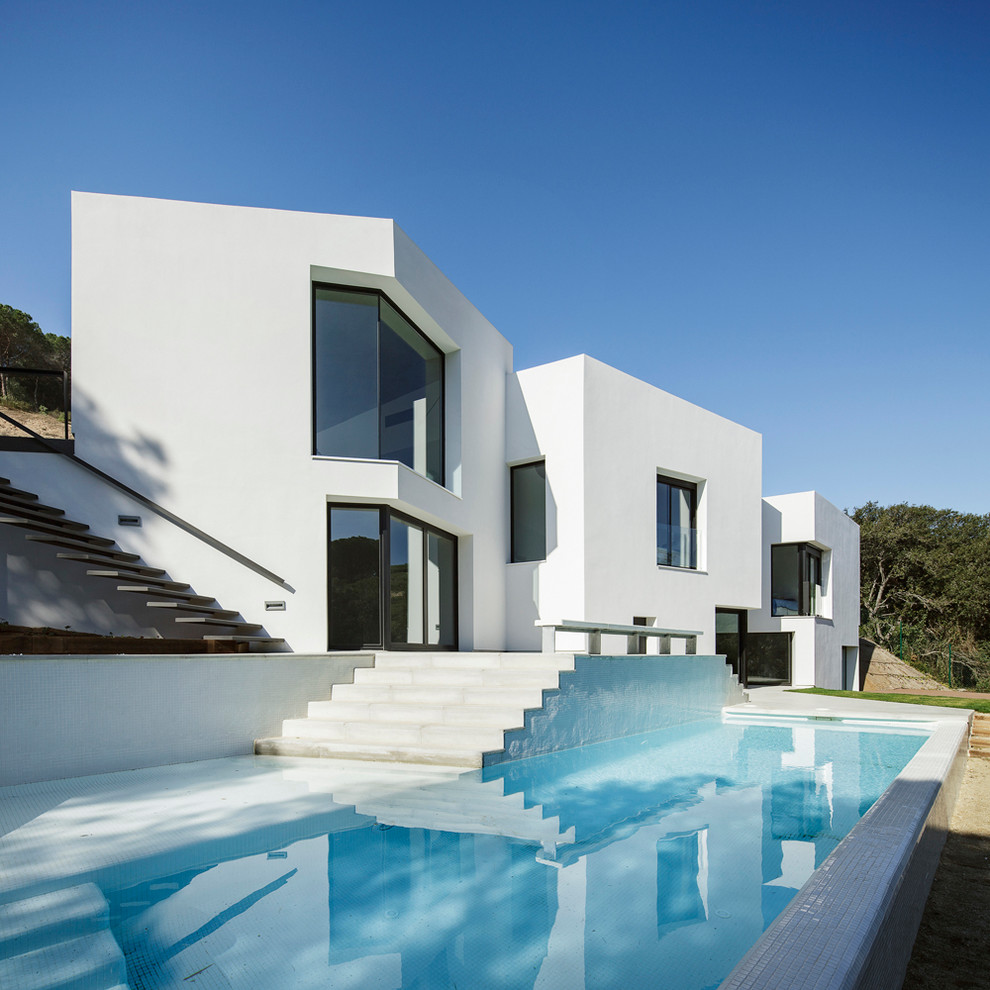 Inspiration for a large contemporary two-storey stucco white exterior in Barcelona with a flat roof.
