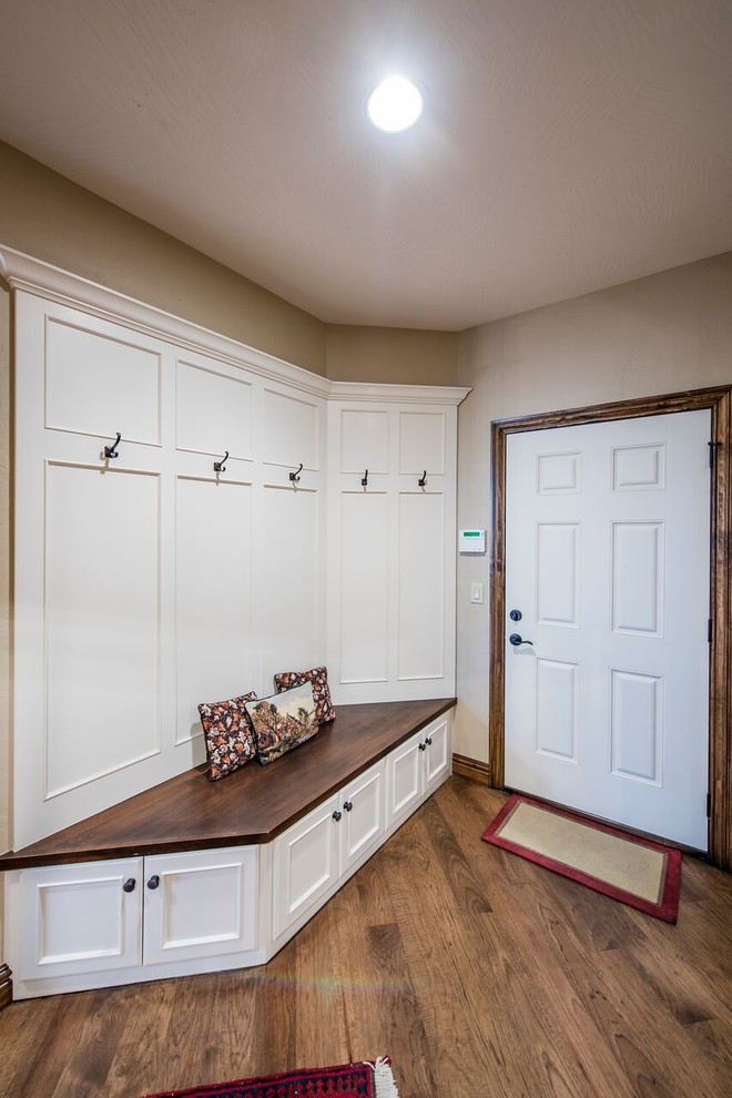 Large mountain style dark wood floor mudroom photo with beige walls and a white front door