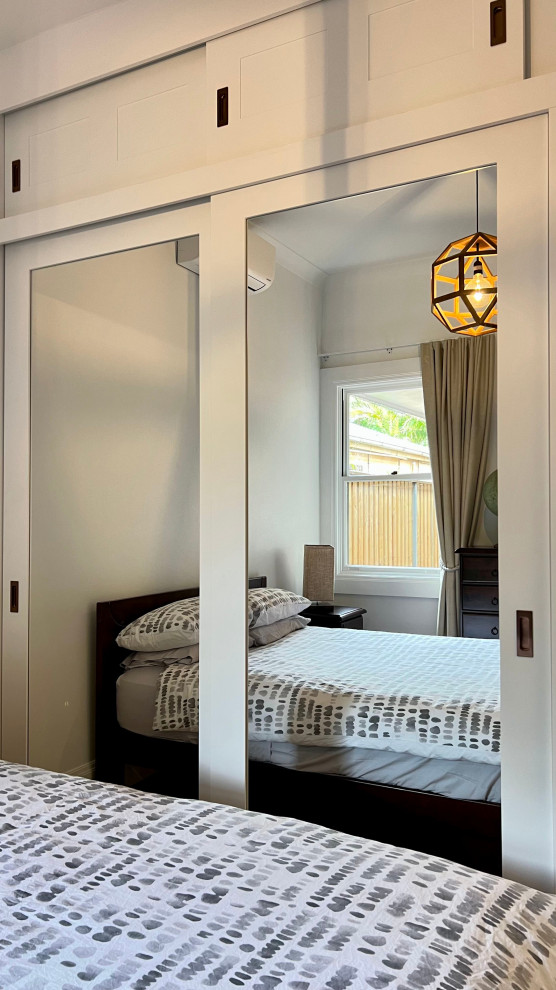 This is an example of a mid-sized contemporary guest bedroom in Sydney with white walls, medium hardwood floors and brown floor.