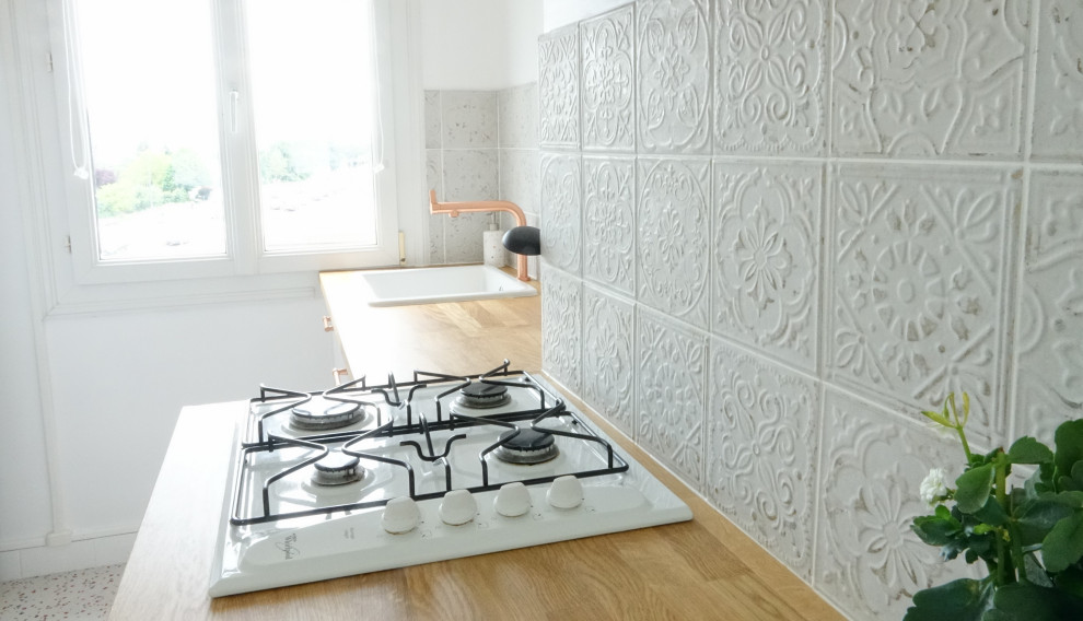 Modern inredning av ett mellanstort beige beige kök, med en undermonterad diskho, luckor med profilerade fronter, träbänkskiva, vitt stänkskydd, stänkskydd i keramik, vita vitvaror, terrazzogolv, en halv köksö och beiget golv