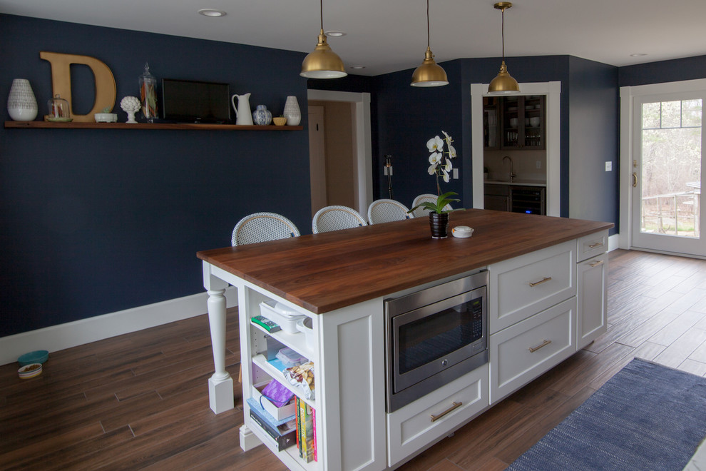 Example of a large transitional l-shaped enclosed kitchen design in Boston with a farmhouse sink, shaker cabinets, white cabinets, quartz countertops, white backsplash, stainless steel appliances, an island and white countertops