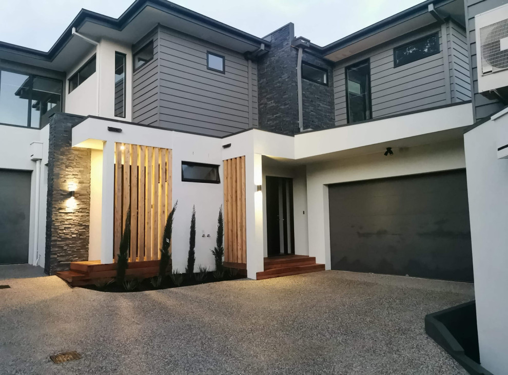 Inspiration for a mid-sized contemporary two-storey multi-coloured townhouse exterior in Melbourne with concrete fiberboard siding, a hip roof, a metal roof, a black roof and board and batten siding.
