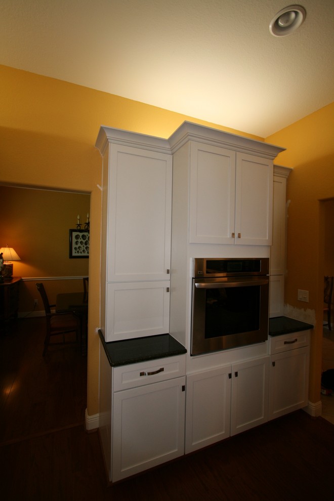 Minimalist eat-in kitchen photo with an undermount sink, flat-panel cabinets, white cabinets, quartzite countertops, white backsplash, porcelain backsplash, stainless steel appliances and an island
