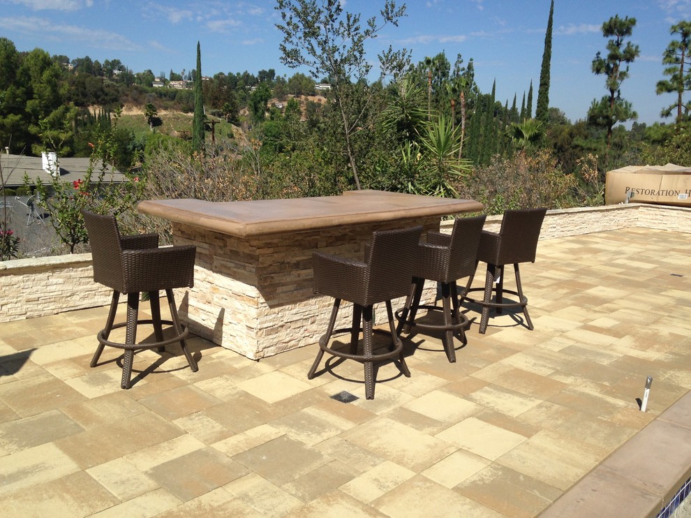 Large modern backyard patio in Los Angeles with an outdoor kitchen, no cover and natural stone pavers.