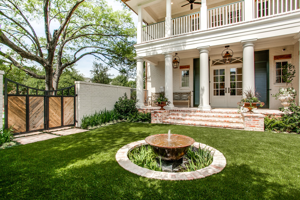 This is an example of a large traditional courtyard shaded formal garden for spring in Dallas with a water feature and brick pavers.