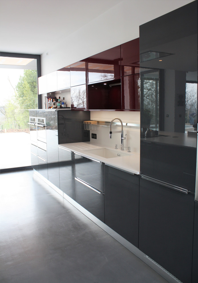 This is an example of an expansive modern galley eat-in kitchen in Other with an integrated sink, beaded inset cabinets, grey cabinets, quartzite benchtops, white splashback, engineered quartz splashback, stainless steel appliances, concrete floors, with island, grey floor, white benchtop and recessed.