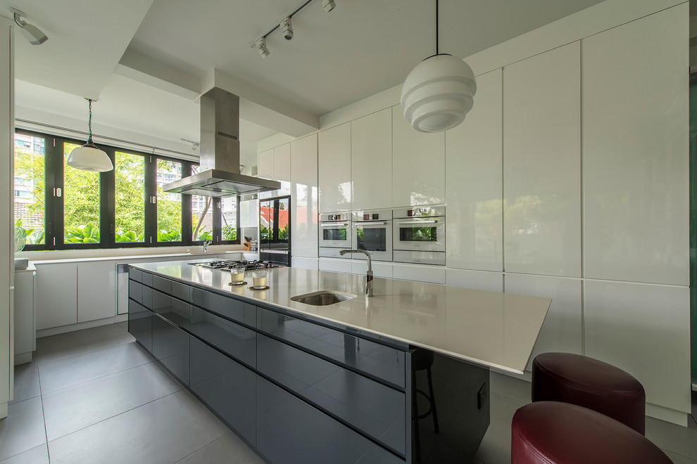 This is an example of a contemporary kitchen in Singapore with an undermount sink, flat-panel cabinets, white cabinets, black appliances and with island.