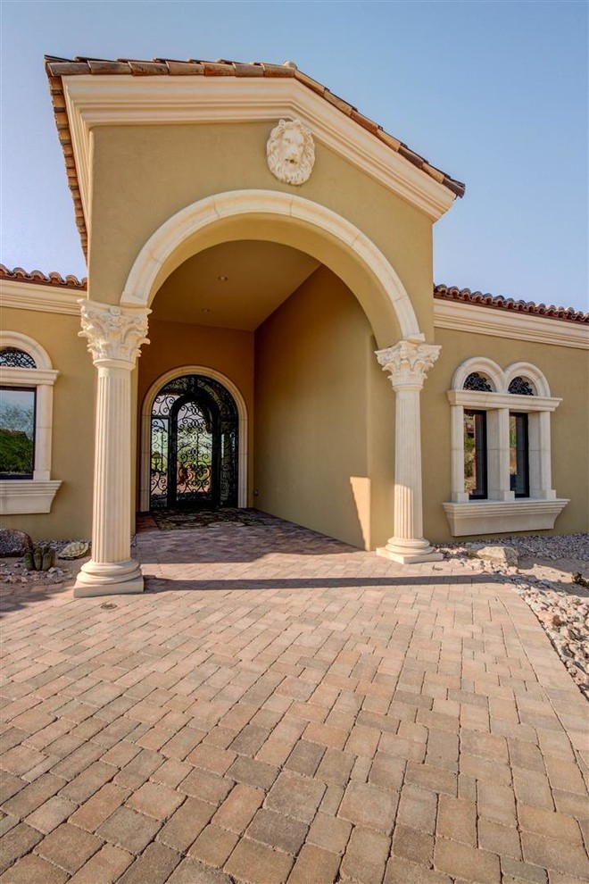 Large mediterranean one-storey stucco beige house exterior in Phoenix with a gable roof and a tile roof.