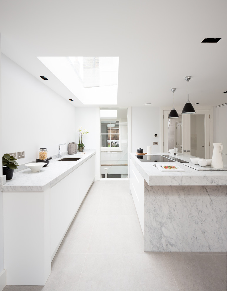 Design ideas for a mid-sized contemporary kitchen in London with flat-panel cabinets, white cabinets, marble benchtops, with island, an integrated sink and slate floors.