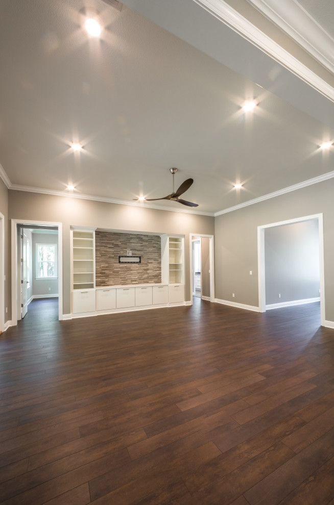This is an example of a mid-sized traditional formal open concept living room with grey walls, vinyl floors, no fireplace, a built-in media wall and brown floor.