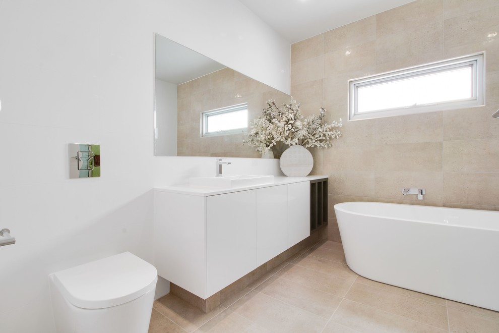 Photo of a large contemporary 3/4 bathroom in Adelaide with a freestanding tub, a one-piece toilet, beige tile, ceramic tile, beige walls and ceramic floors.