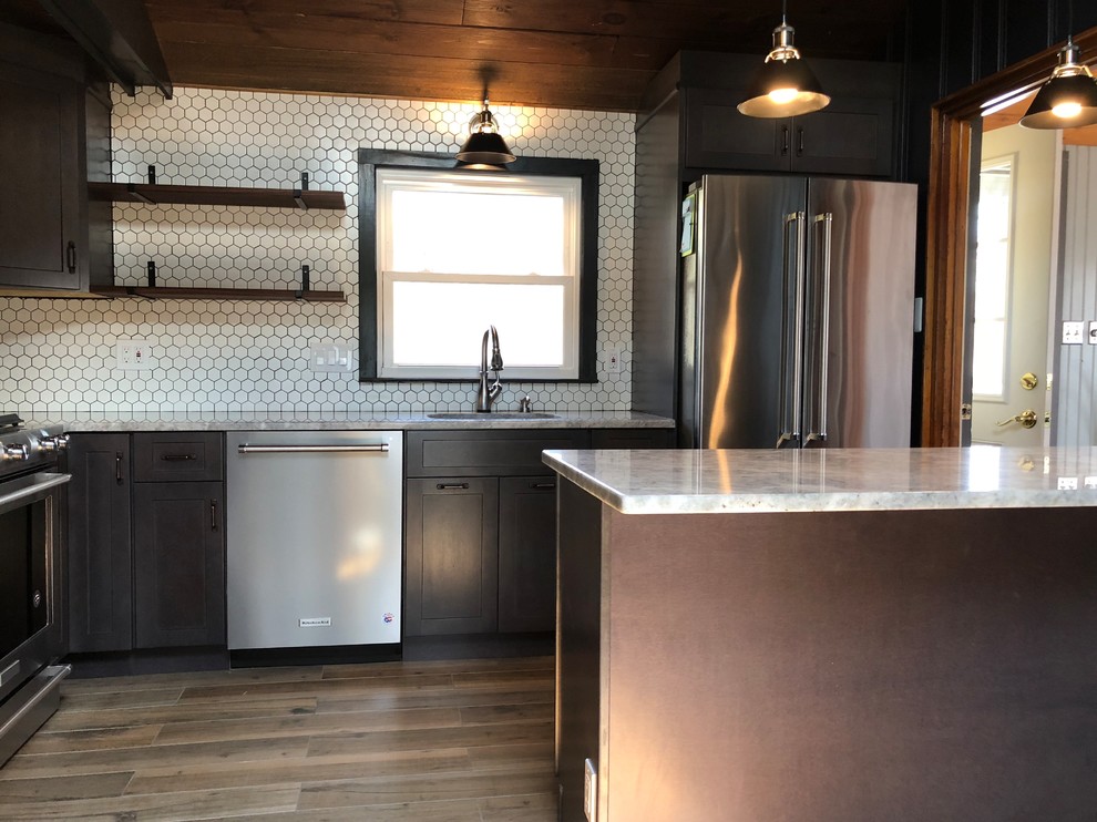 This is an example of a small eclectic galley separate kitchen in New York with an undermount sink, shaker cabinets, brown cabinets, granite benchtops, white splashback, ceramic splashback, stainless steel appliances, porcelain floors, a peninsula, brown floor and white benchtop.