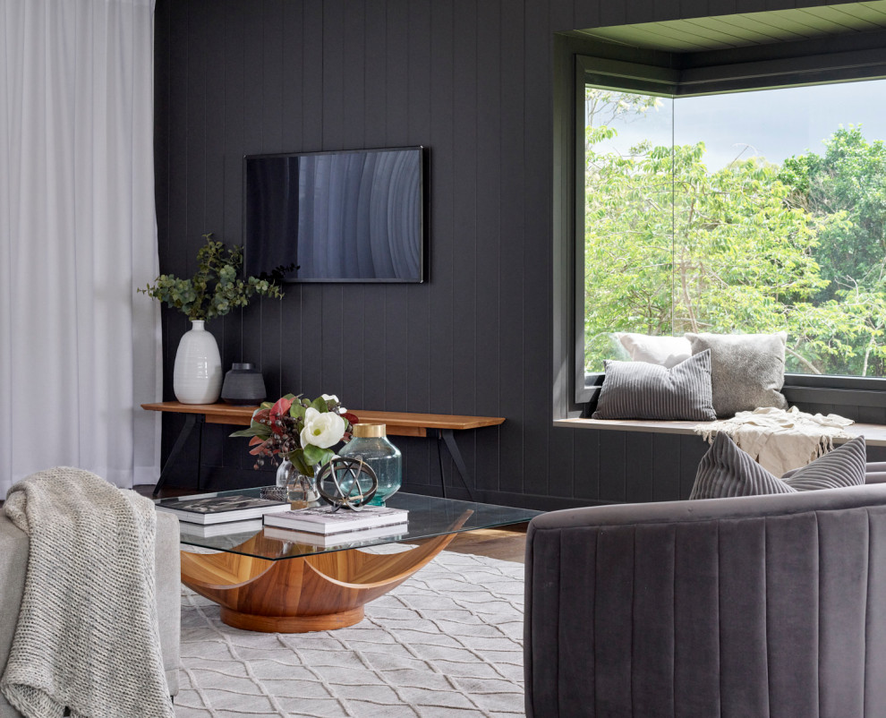 This is an example of a large contemporary open concept living room in Brisbane with black walls, medium hardwood floors, a wall-mounted tv, brown floor and planked wall panelling.