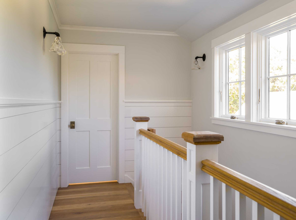 Mid-sized beach style hallway in Boston with white walls, light hardwood floors and brown floor.