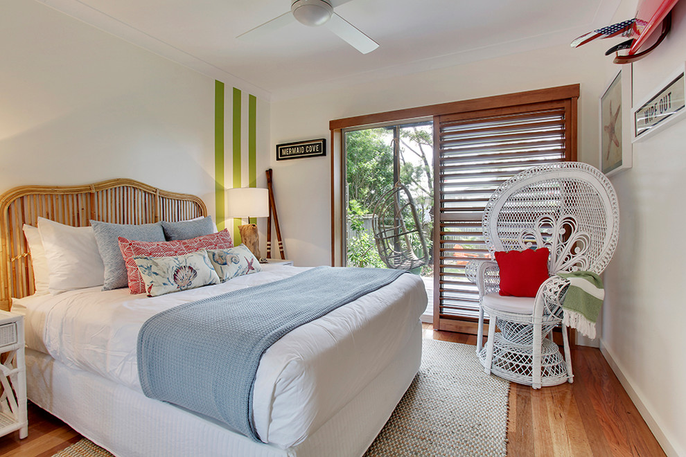 Photo of a beach style bedroom in Sydney with white walls and light hardwood floors.