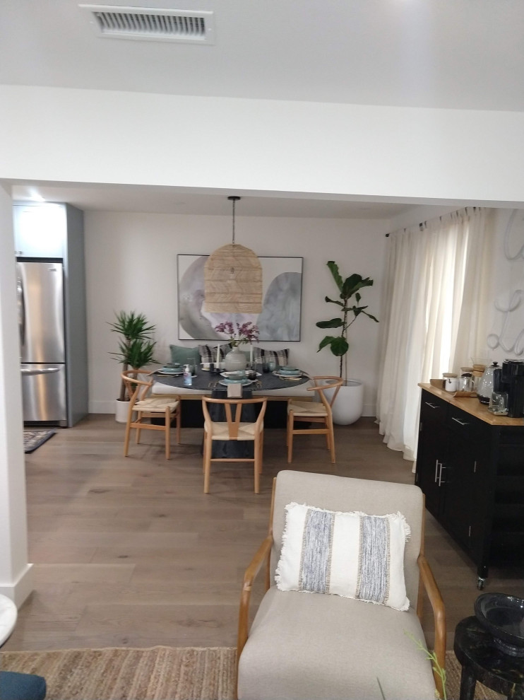 Foto di una sala da pranzo aperta verso la cucina moderna di medie dimensioni con pareti bianche, pavimento in legno massello medio e pavimento marrone
