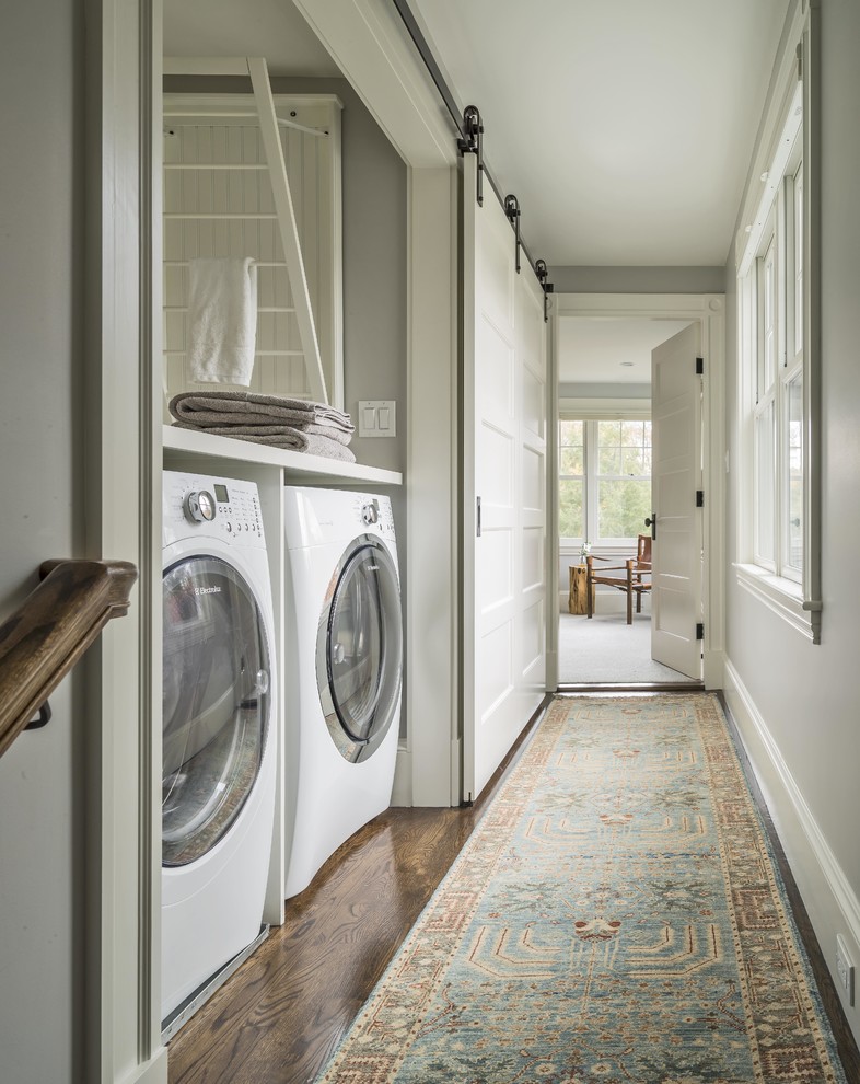 This is an example of a small country single-wall laundry cupboard in Boston with shaker cabinets, white cabinets, wood benchtops, grey walls, a side-by-side washer and dryer and white benchtop.