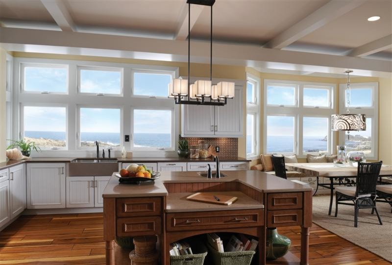 Large beach style l-shaped medium tone wood floor and brown floor open concept kitchen photo in Denver with a farmhouse sink, beaded inset cabinets, white cabinets, solid surface countertops, brown backsplash, mosaic tile backsplash, stainless steel appliances and an island