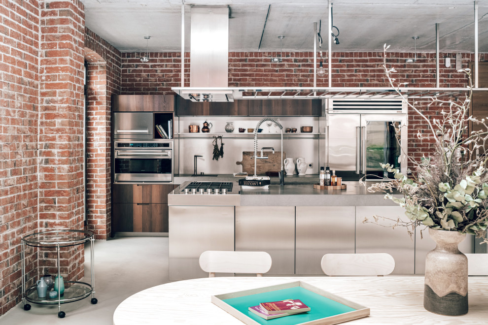 Esempio di una grande sala da pranzo aperta verso la cucina design con pareti rosse, pavimento in cemento, stufa a legna, cornice del camino in metallo e pavimento grigio