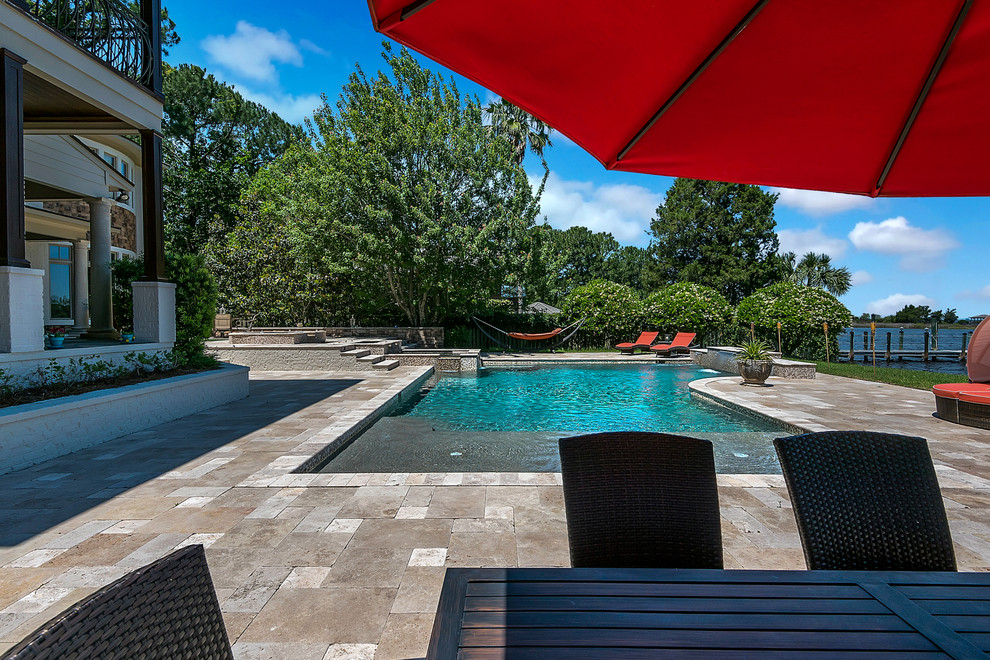 Large traditional backyard custom-shaped pool in Jacksonville with a hot tub and natural stone pavers.
