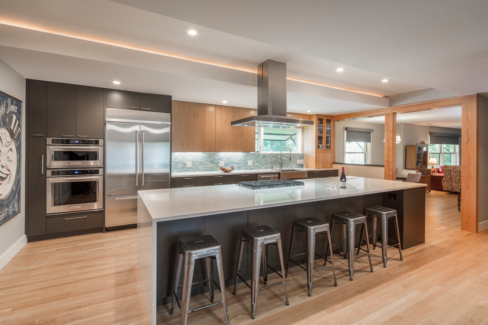 Inspiration for a contemporary galley open plan kitchen in Austin with a farmhouse sink, flat-panel cabinets, grey cabinets, blue splashback, mosaic tile splashback, stainless steel appliances, light hardwood floors, with island and beige floor.