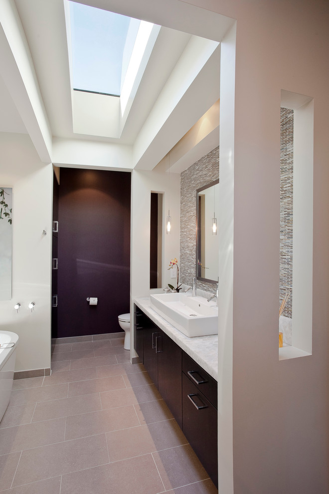 This is an example of a contemporary bathroom in San Francisco with a trough sink, flat-panel cabinets, dark wood cabinets, a freestanding tub, mosaic tile and gray tile.