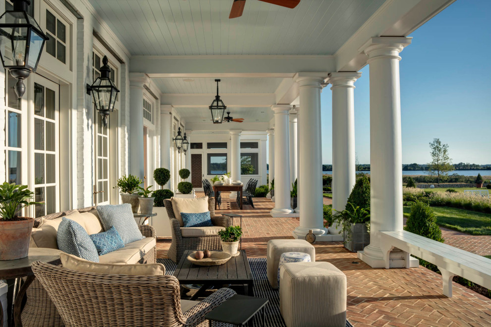 Expansive traditional backyard verandah in Baltimore with with columns, concrete pavers and a roof extension.