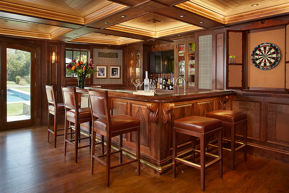 Photo of a large traditional u-shaped seated home bar in San Francisco with glass-front cabinets, medium wood cabinets, wood benchtops and medium hardwood floors.
