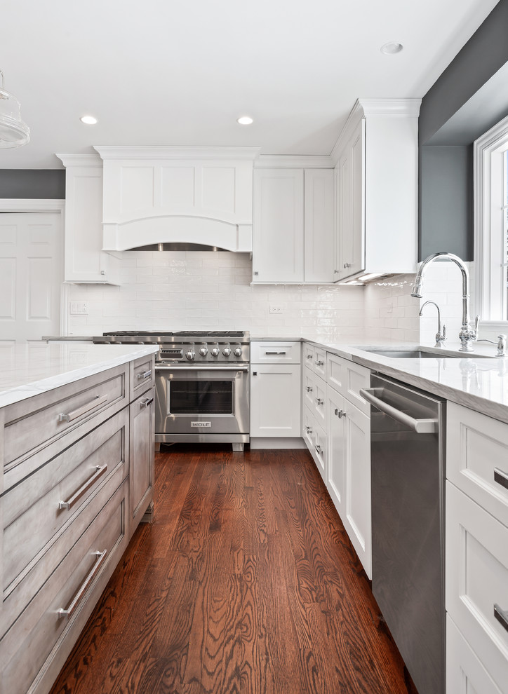 Eat-in kitchen - large transitional u-shaped medium tone wood floor and brown floor eat-in kitchen idea in Chicago with a single-bowl sink, shaker cabinets, white cabinets, quartzite countertops, white backsplash, porcelain backsplash, stainless steel appliances, an island and gray countertops