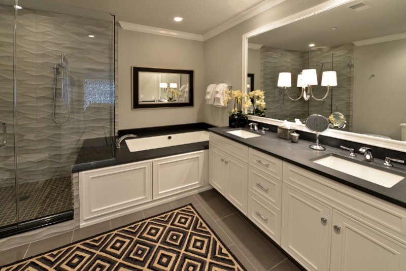 Photo of a mid-sized contemporary master bathroom in Philadelphia with recessed-panel cabinets, white cabinets, an undermount tub, a corner shower, gray tile, porcelain tile, grey walls, porcelain floors, an undermount sink, soapstone benchtops, grey floor and a hinged shower door.