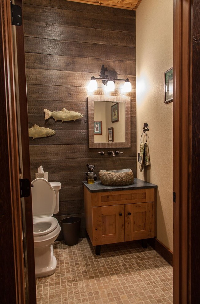Small mountain style ceramic tile and beige floor powder room photo with shaker cabinets, medium tone wood cabinets, a two-piece toilet, beige walls, a vessel sink and soapstone countertops