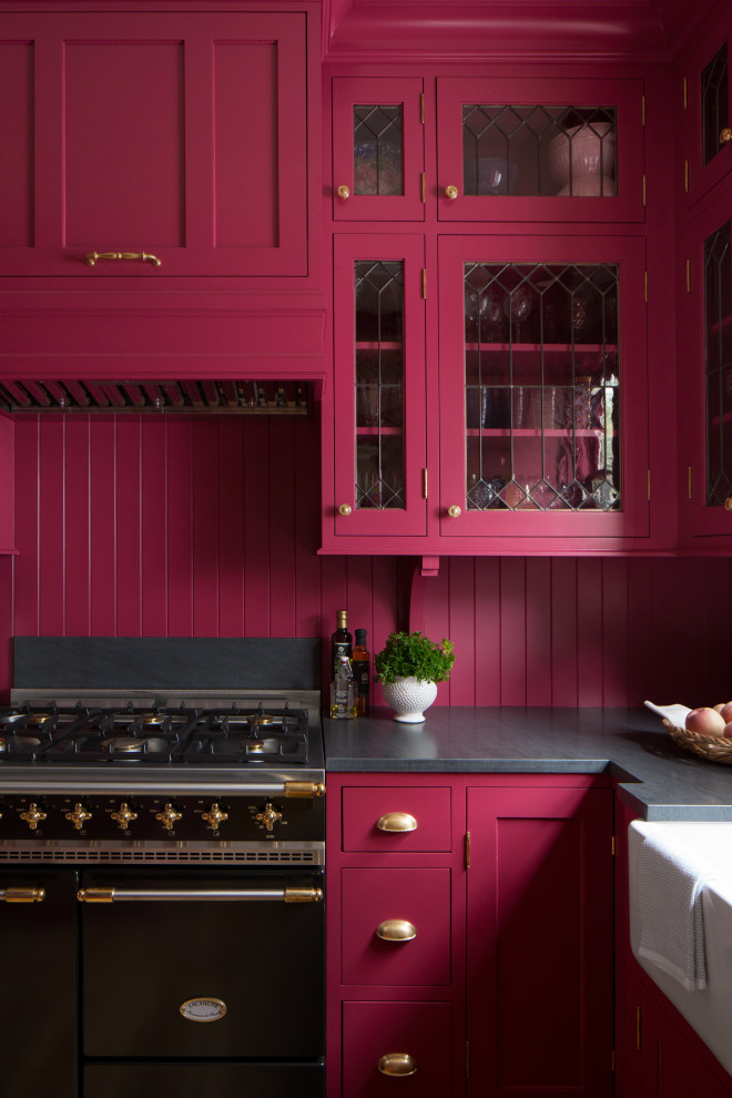 Inspiration for a small traditional l-shaped separate kitchen in Seattle with a farmhouse sink, shaker cabinets, pink cabinets, granite benchtops, pink splashback, timber splashback, panelled appliances, light hardwood floors, no island, brown floor and black benchtop.