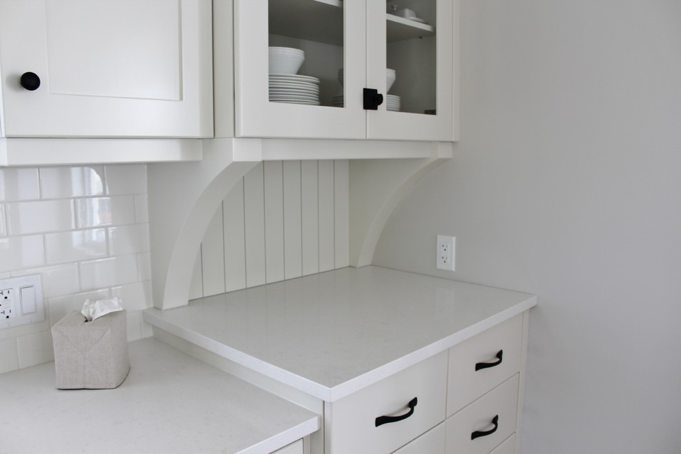 Example of a large transitional l-shaped eat-in kitchen design in Toronto with an undermount sink, shaker cabinets, white cabinets, quartz countertops, white backsplash, stainless steel appliances and an island