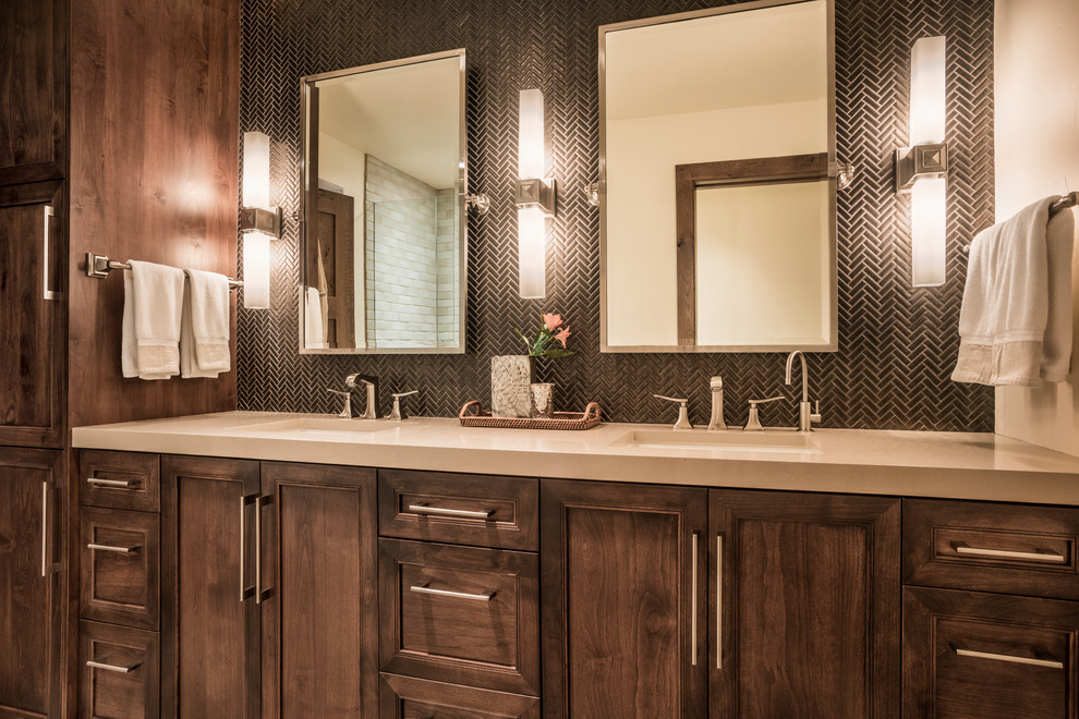 This is an example of a mid-sized country bathroom in Denver with an undermount sink, recessed-panel cabinets, dark wood cabinets, solid surface benchtops, black tile, mosaic tile, beige walls, a corner shower and a hinged shower door.
