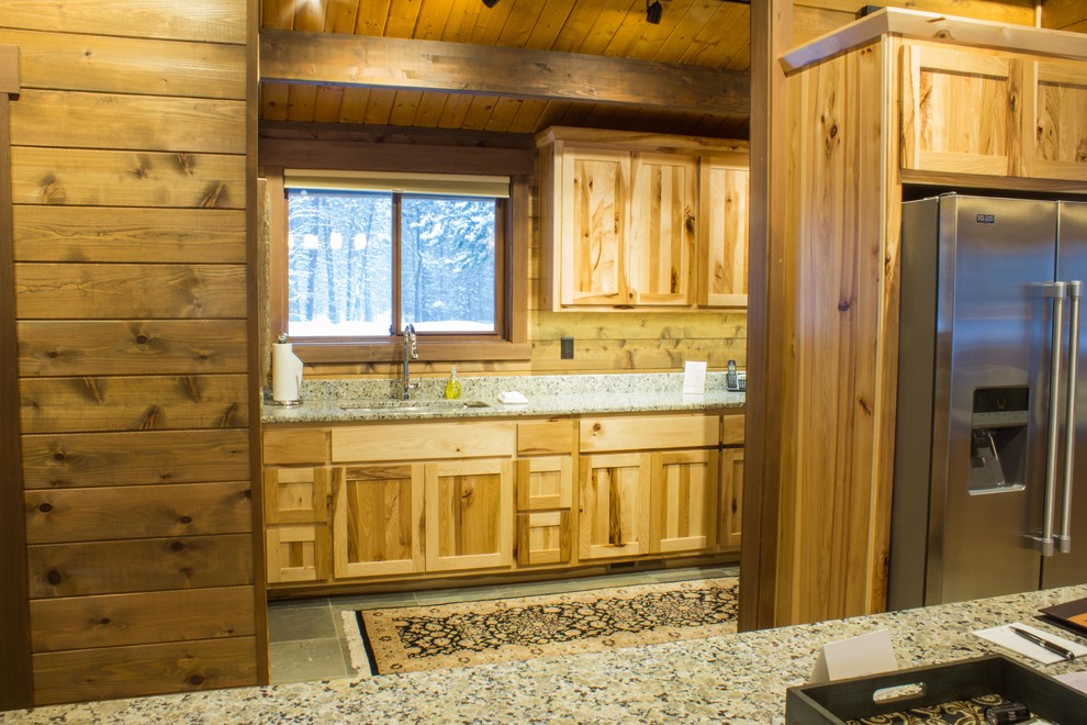 Example of a mid-sized mountain style l-shaped slate floor and gray floor eat-in kitchen design with flat-panel cabinets, medium tone wood cabinets, granite countertops, stainless steel appliances, an island and an undermount sink