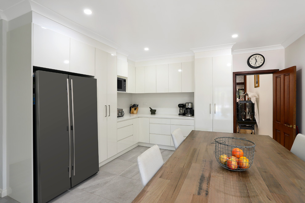 Inspiration for a mid-sized modern l-shaped eat-in kitchen in Sydney with an undermount sink, flat-panel cabinets, white cabinets, quartz benchtops, white splashback, slate splashback, stainless steel appliances, porcelain floors, no island, grey floor and white benchtop.