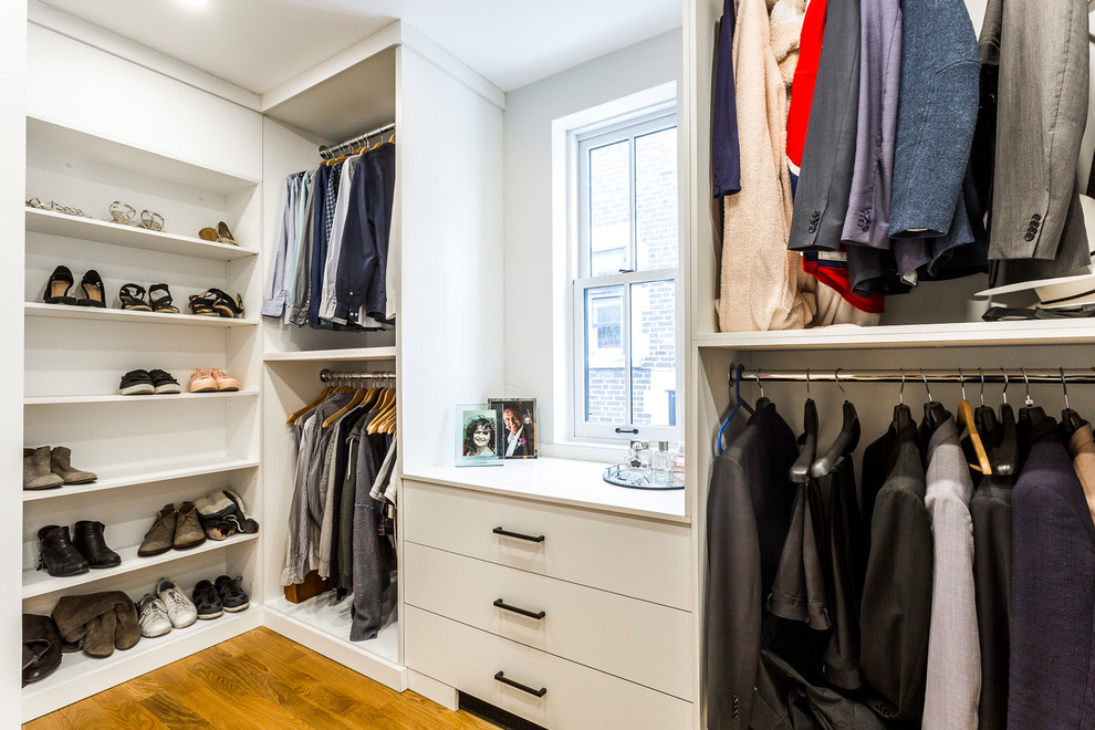 This is an example of a mid-sized modern gender-neutral walk-in wardrobe in Montreal with flat-panel cabinets, white cabinets, light hardwood floors and yellow floor.