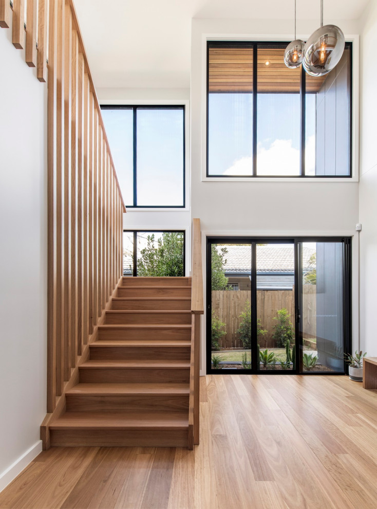 Large contemporary wood u-shaped staircase with wood risers and wood railing.