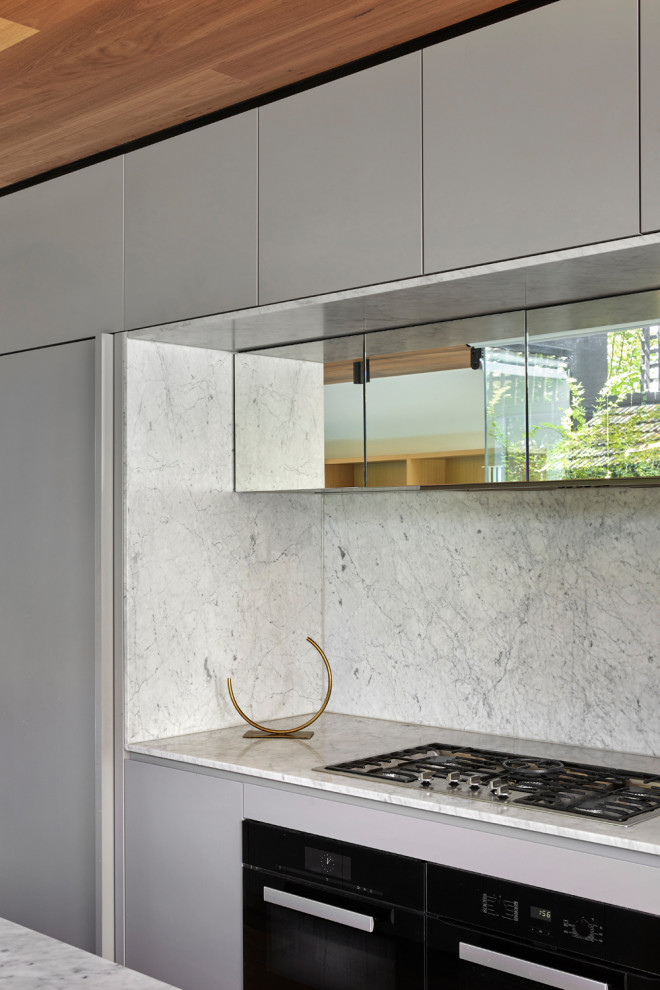 Medium sized contemporary galley open plan kitchen in Melbourne with medium hardwood flooring, a timber clad ceiling, a submerged sink, grey cabinets, marble worktops, marble splashback, black appliances, an island and white worktops.