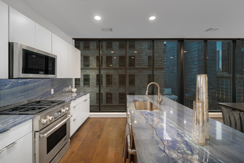 Cette photo montre une cuisine moderne avec un évier encastré, un placard à porte plane, un plan de travail en quartz, une crédence bleue, îlot et un plan de travail bleu.
