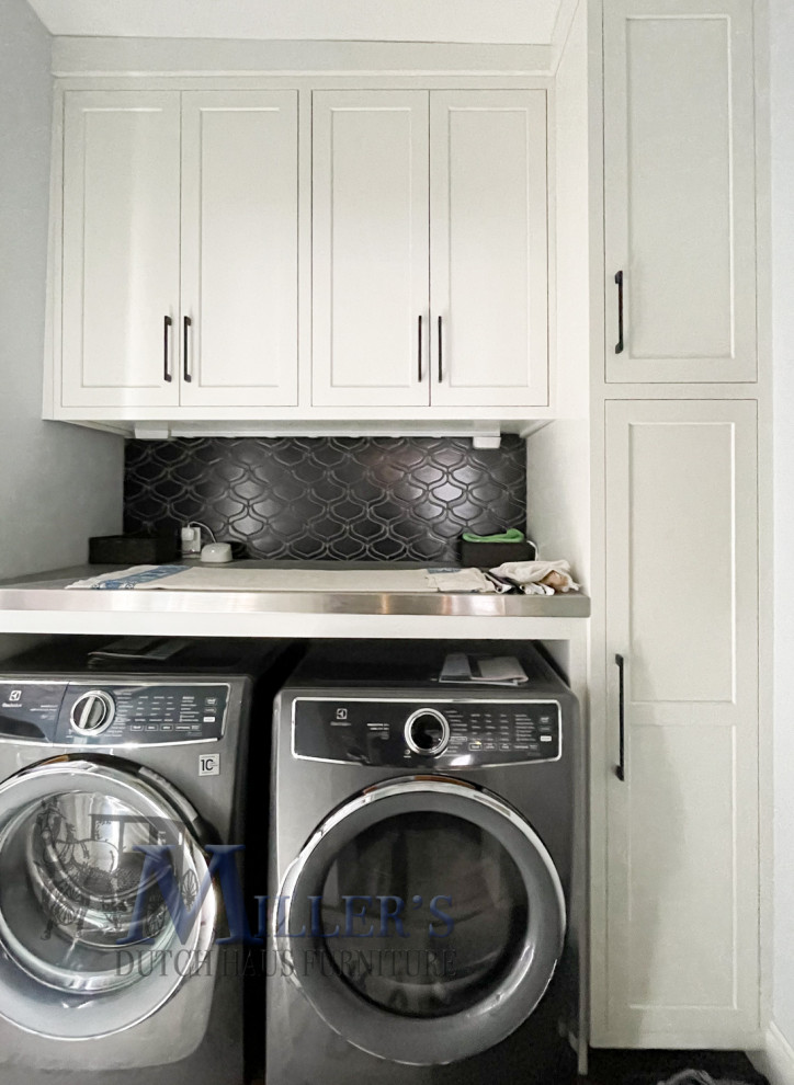 Exempel på en mellanstor klassisk linjär tvättstuga enbart för tvätt, med luckor med infälld panel, vita skåp, bänkskiva i rostfritt stål, vita väggar och en tvättmaskin och torktumlare bredvid varandra