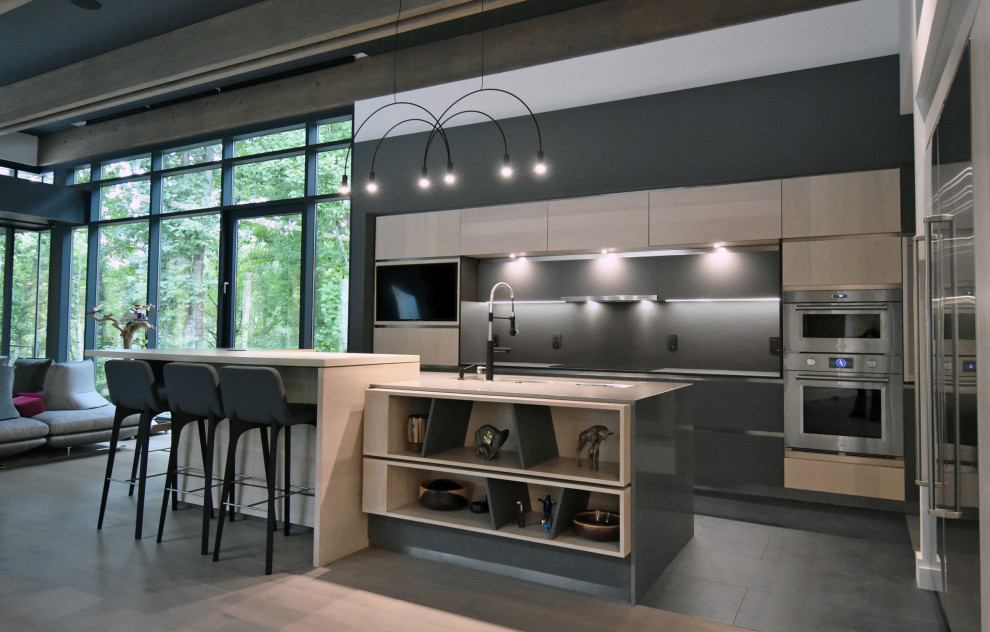 Bild på ett mellanstort funkis grå grått kök, med en undermonterad diskho, släta luckor, skåp i ljust trä, bänkskiva i kvarts, svart stänkskydd, rostfria vitvaror, mellanmörkt trägolv, en köksö och beiget golv